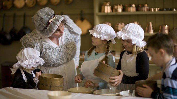 Children enjoying a period recreation of a kitchen with the help of a costumed interpreter at Attingham Park